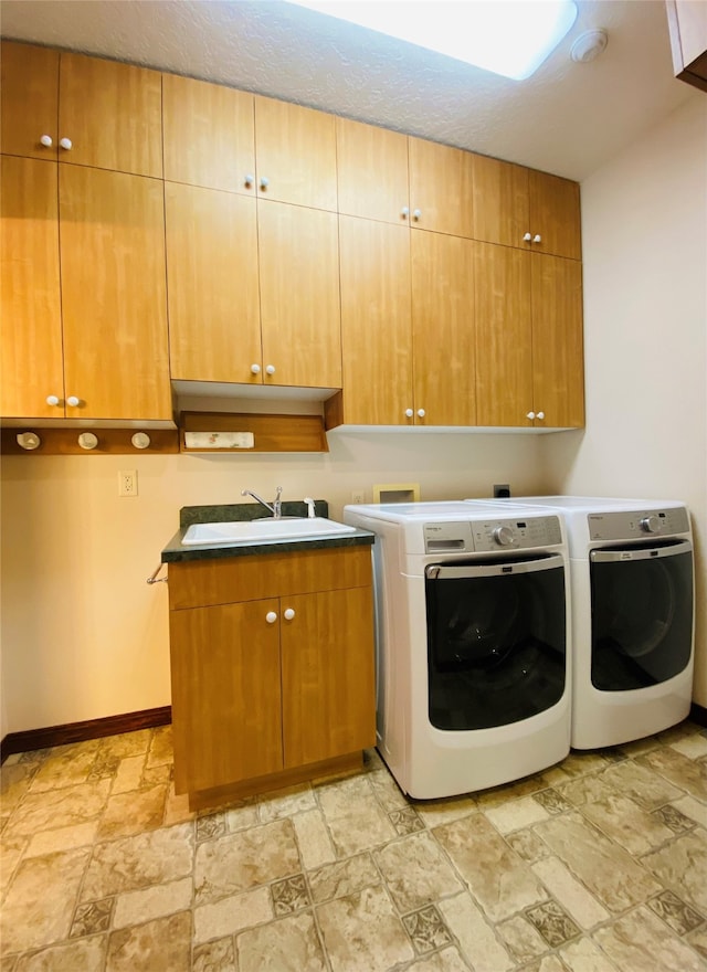 clothes washing area with cabinets, washing machine and clothes dryer, and sink