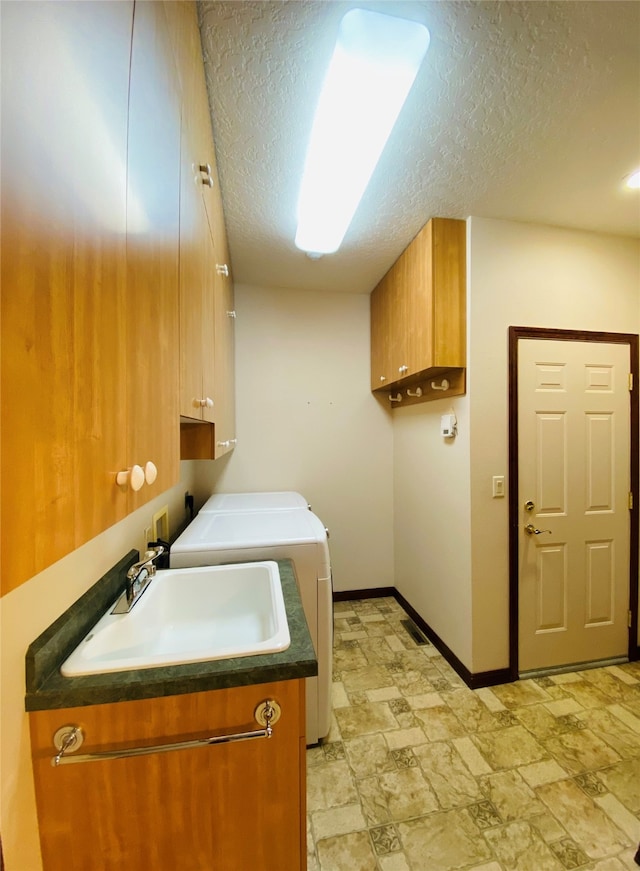 laundry area with a textured ceiling, cabinets, independent washer and dryer, and sink