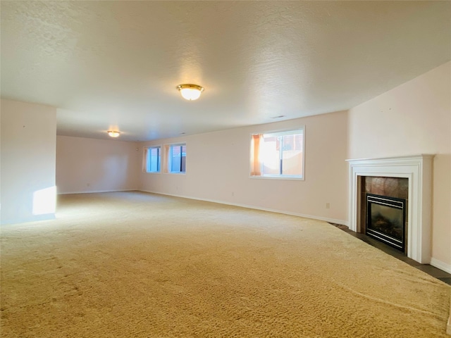 unfurnished living room featuring carpet floors, a textured ceiling, and a tiled fireplace