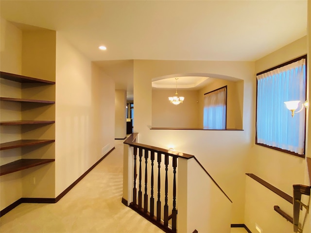 staircase featuring carpet, a tray ceiling, and a notable chandelier