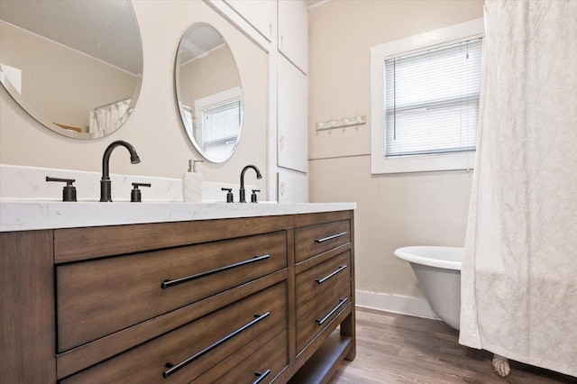 bathroom with a washtub, wood-type flooring, and vanity