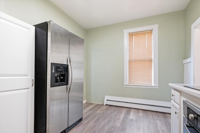 kitchen with white cabinets, a baseboard heating unit, stainless steel appliances, and light hardwood / wood-style flooring