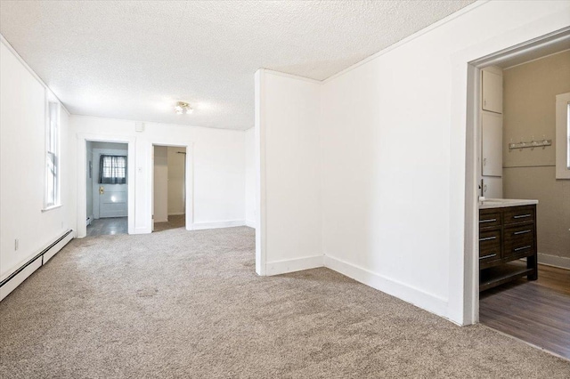 carpeted spare room featuring a textured ceiling, a baseboard heating unit, and crown molding