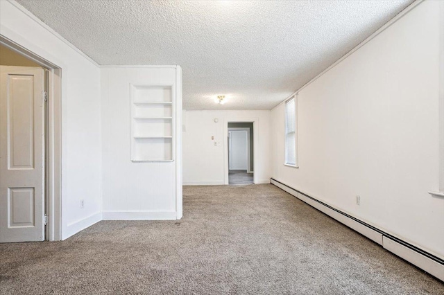 carpeted spare room with a baseboard heating unit, a textured ceiling, and built in shelves