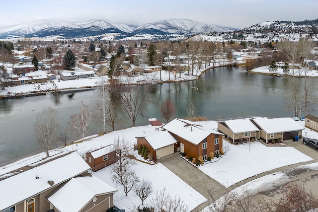 snowy aerial view featuring a water and mountain view