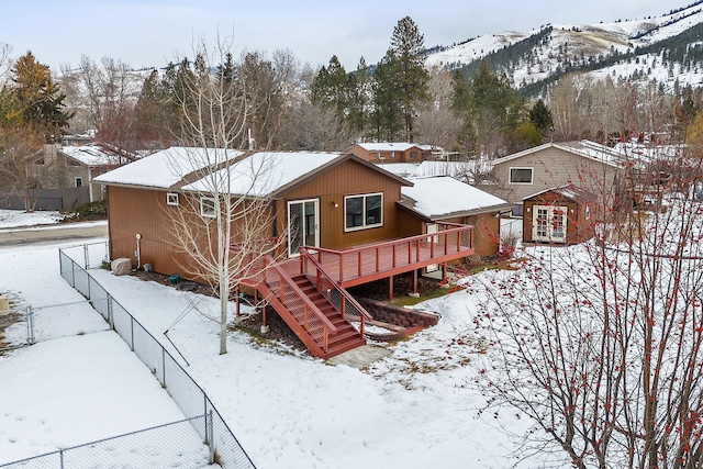 snow covered back of property featuring a deck with mountain view and a shed