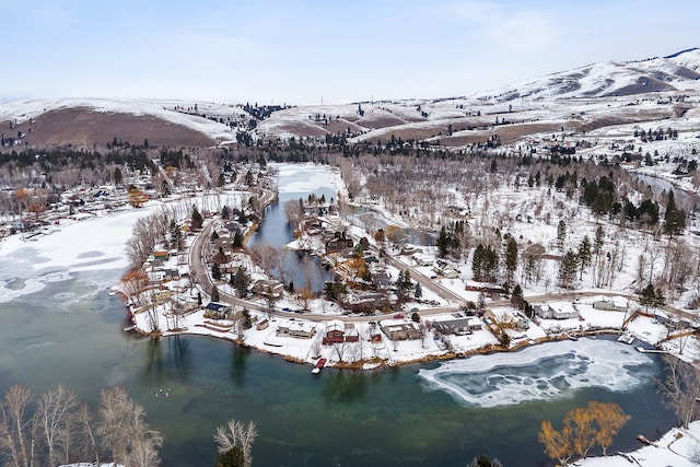 snowy aerial view with a water and mountain view