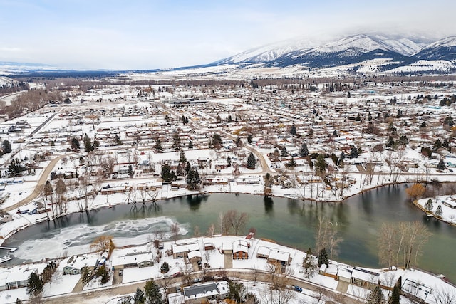 snowy aerial view featuring a water and mountain view