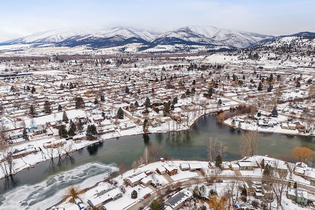 snowy aerial view featuring a water and mountain view