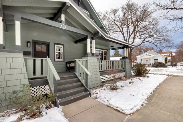 snow covered property entrance with covered porch