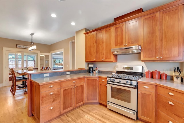 kitchen with light hardwood / wood-style floors, hanging light fixtures, kitchen peninsula, and stainless steel gas range oven