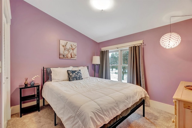 bedroom featuring a closet, light colored carpet, and lofted ceiling