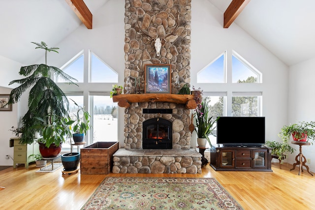 living room featuring high vaulted ceiling, wood-type flooring, beamed ceiling, and a stone fireplace