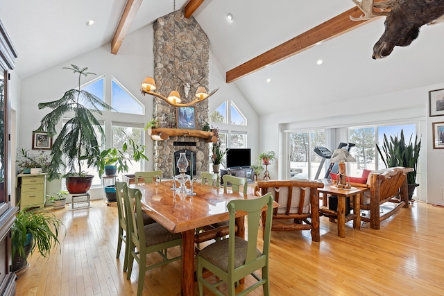 dining room featuring beamed ceiling, a fireplace, a chandelier, light wood-type flooring, and high vaulted ceiling