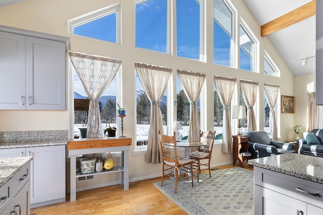 interior space with light stone countertops, vaulted ceiling with beams, gray cabinets, and light wood-type flooring