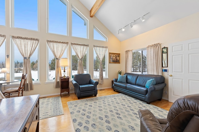 living room featuring a high ceiling, light hardwood / wood-style flooring, and beamed ceiling