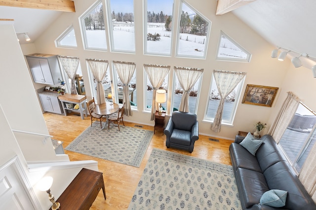 living room featuring light wood-type flooring, high vaulted ceiling, and beam ceiling