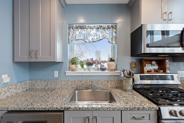 kitchen with washer / dryer, light stone countertops, sink, stainless steel appliances, and gray cabinets