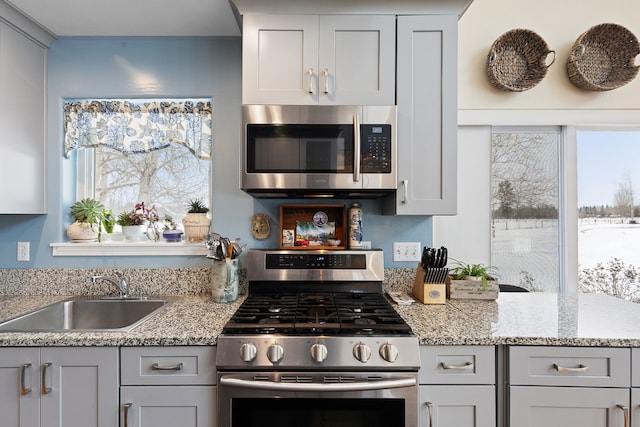 kitchen featuring sink, light stone counters, appliances with stainless steel finishes, and gray cabinets