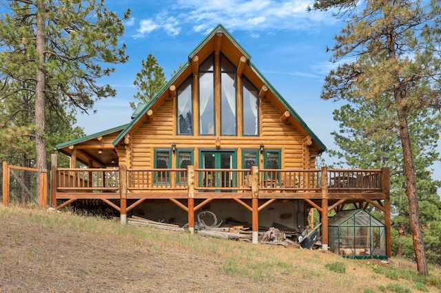 2122 Lightning Draw Trl, Victor, MT 59875 - back of house featuring log siding, a wooden deck, and a greenhouse