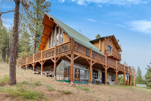 2122 Lightning Draw Trl, Victor, MT 59875 - back of property featuring a deck, metal roof, log exterior, and a greenhouse