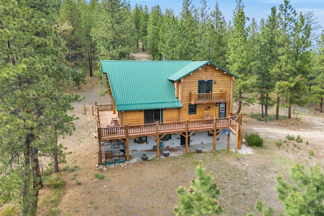 2122 Lightning Draw Trl, Victor, MT 59875 - back of house with a wooden deck, metal roof, a balcony, and a wooded view