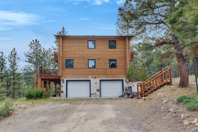 2122 Lightning Draw Trl, Victor, MT 59875 - view of property exterior featuring log siding, dirt driveway, a garage, and a wooden deck