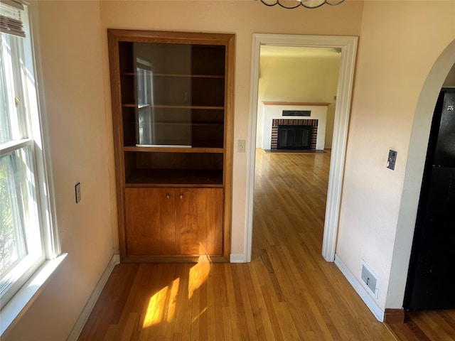 hall with arched walkways, baseboards, and wood finished floors
