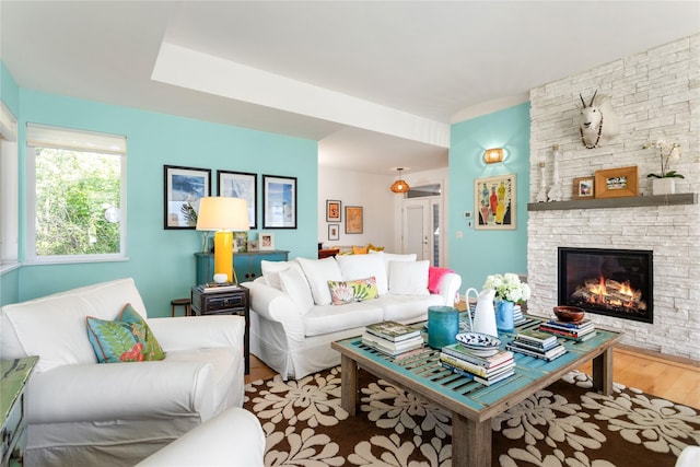 living room featuring light wood-type flooring and a stone fireplace