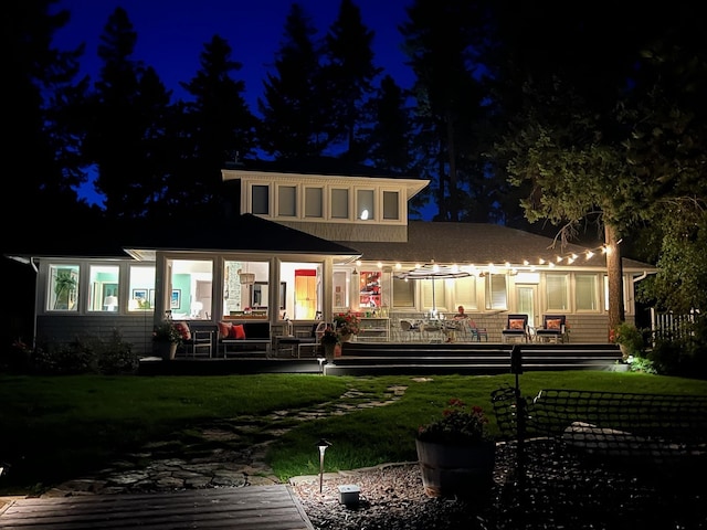 back house at twilight with a lawn