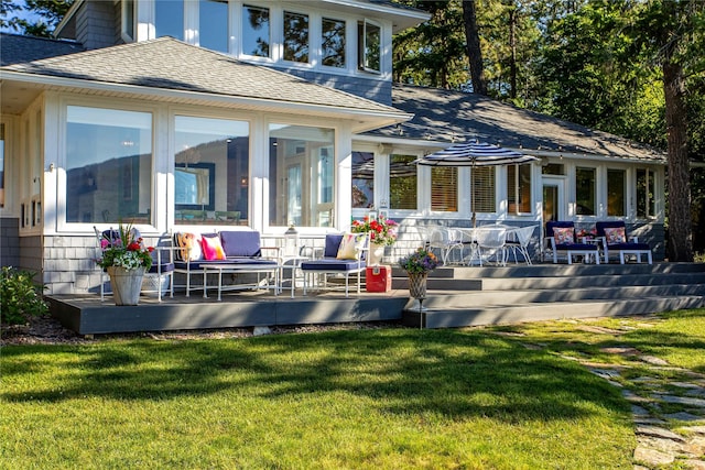 back of property featuring a sunroom, a lawn, and a deck