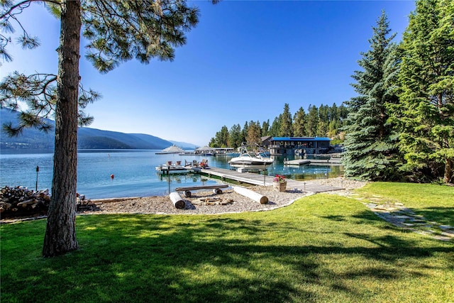 view of dock with a water and mountain view and a lawn