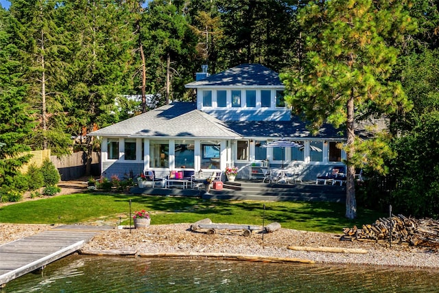 rear view of property featuring a water view, outdoor lounge area, and a yard