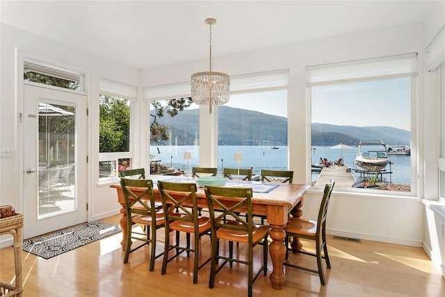 sunroom / solarium featuring a water and mountain view and a notable chandelier