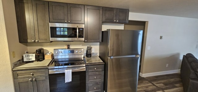 kitchen featuring dark wood-type flooring, appliances with stainless steel finishes, and dark brown cabinets