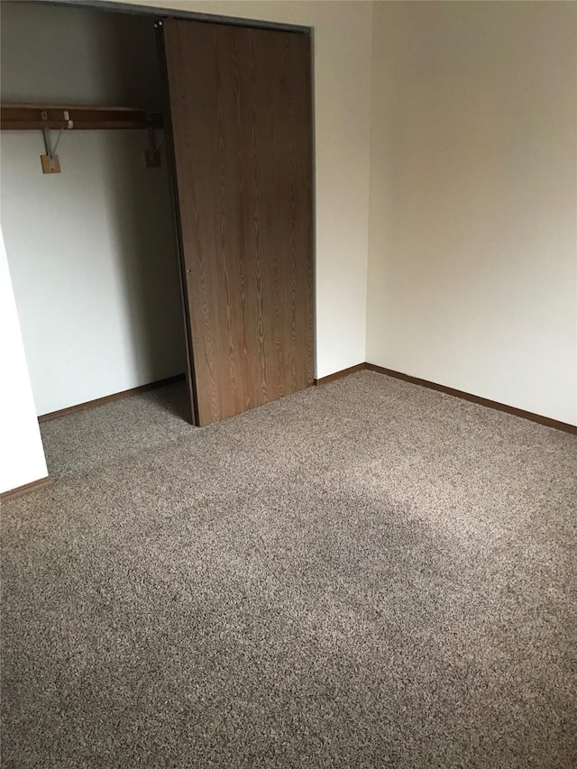 unfurnished bedroom featuring a closet and dark carpet