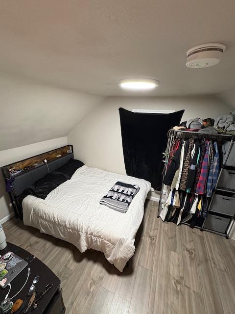 bedroom with lofted ceiling and wood-type flooring