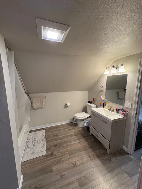 bathroom featuring lofted ceiling, toilet, a textured ceiling, vanity, and hardwood / wood-style floors