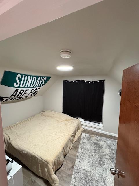 bedroom with wood-type flooring and vaulted ceiling