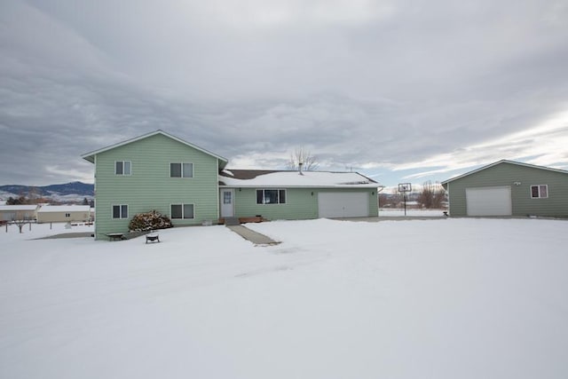 snow covered house featuring a garage and an outdoor structure