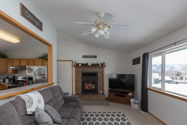 carpeted living room with a fireplace, vaulted ceiling, and ceiling fan