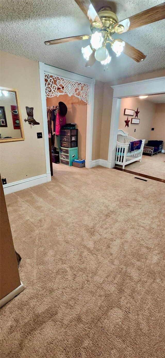 interior space with ceiling fan, a textured ceiling, and carpet