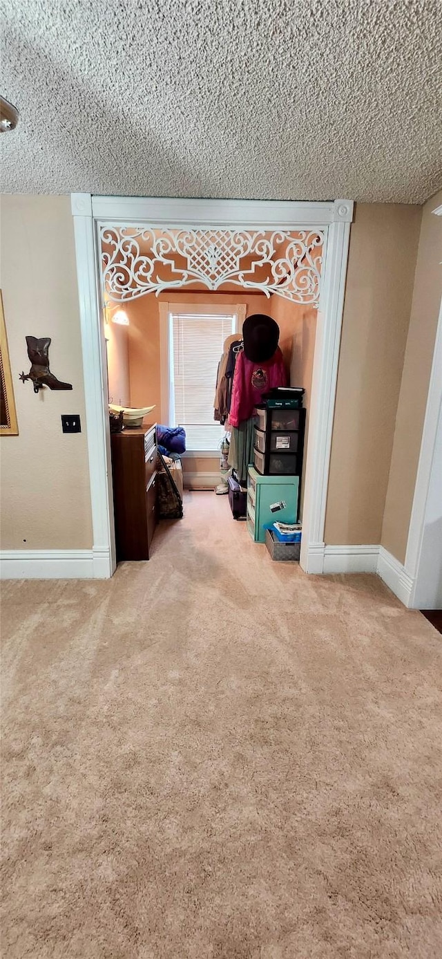 hallway featuring carpet flooring and a textured ceiling