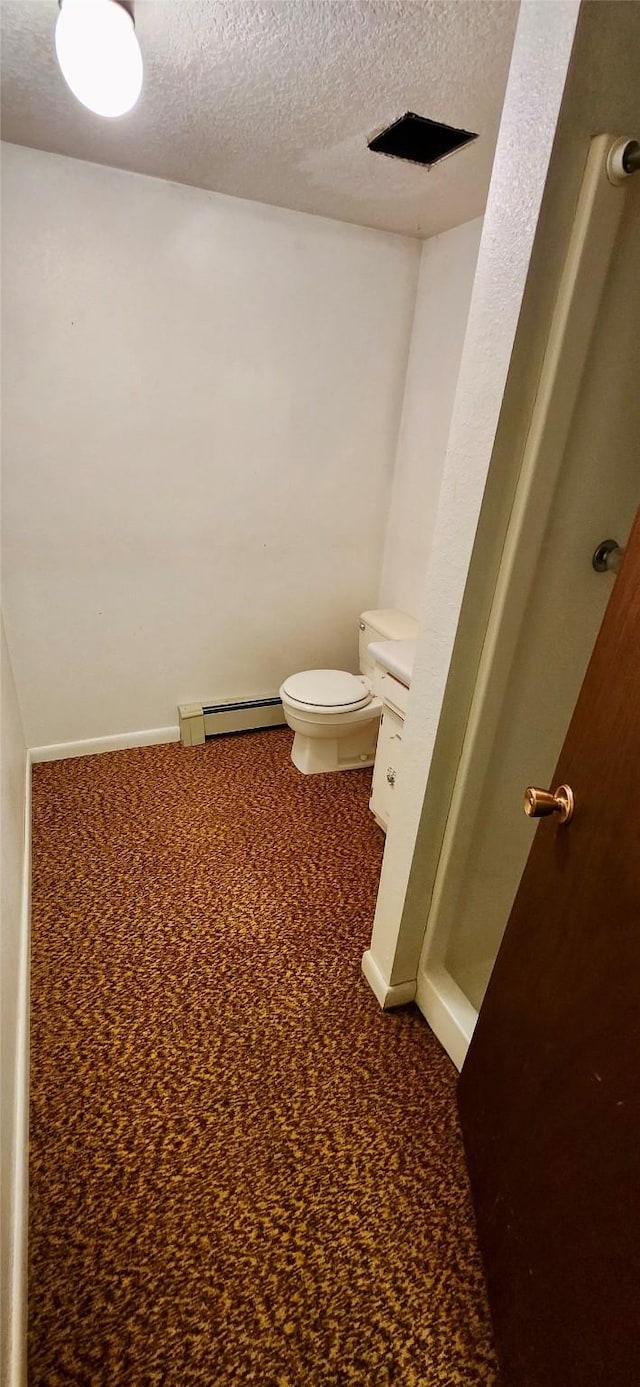 bathroom with toilet, a baseboard radiator, and a textured ceiling