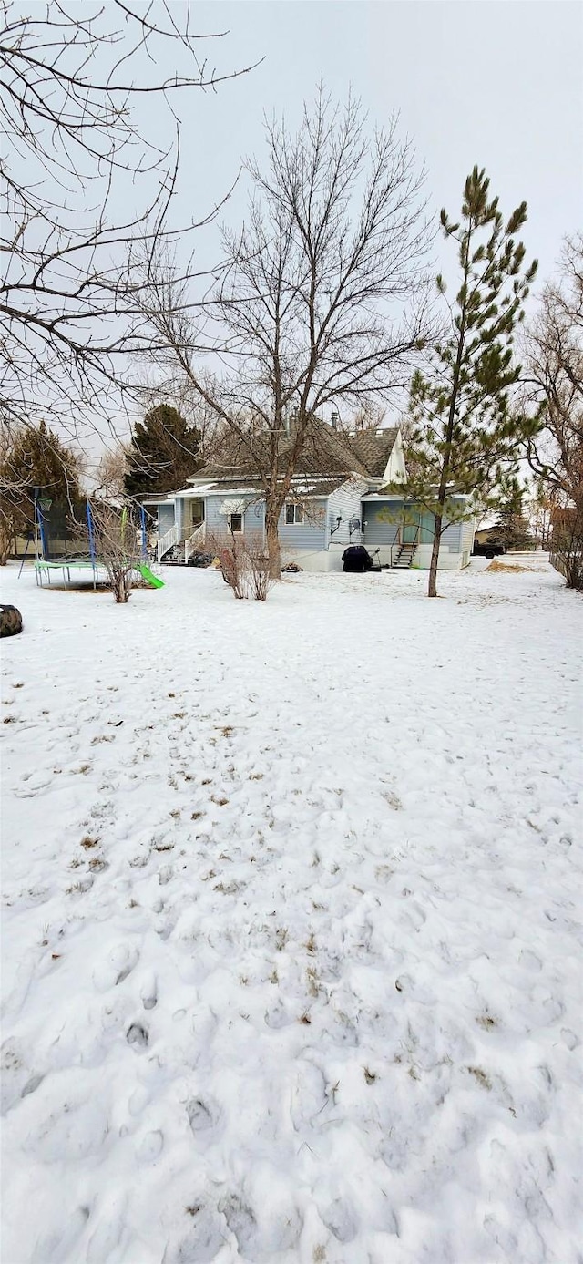 yard layered in snow with a trampoline