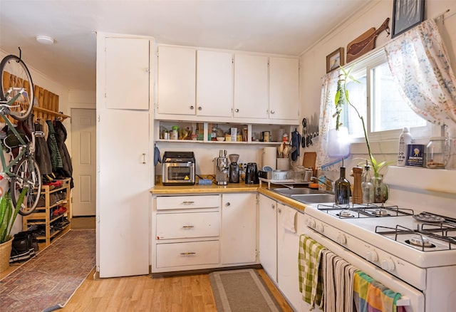 kitchen with white gas range, sink, white cabinetry, and light hardwood / wood-style flooring