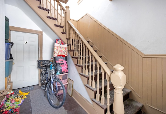 stairway featuring wooden walls