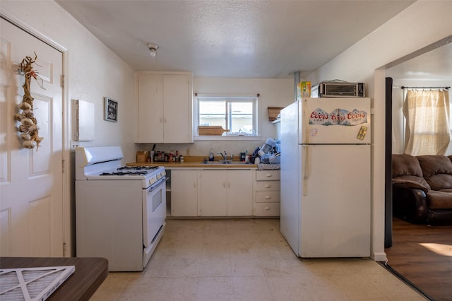 kitchen featuring sink, white appliances, white cabinets, and a textured ceiling