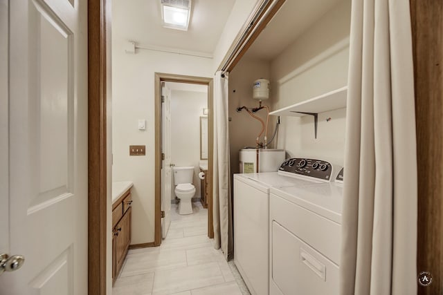 laundry area with light tile patterned flooring, water heater, and washing machine and clothes dryer