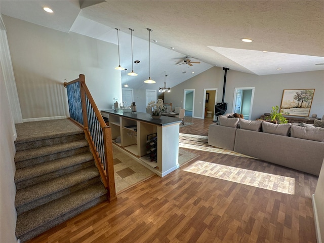 stairs featuring a textured ceiling, ceiling fan, a wood stove, vaulted ceiling, and hardwood / wood-style flooring